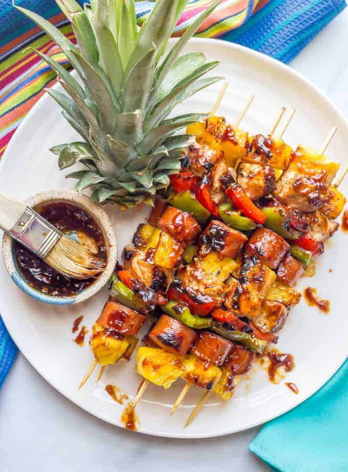 Grilled teriyaki chicken kabobs on a white plate with extra teriyaki sauce on top