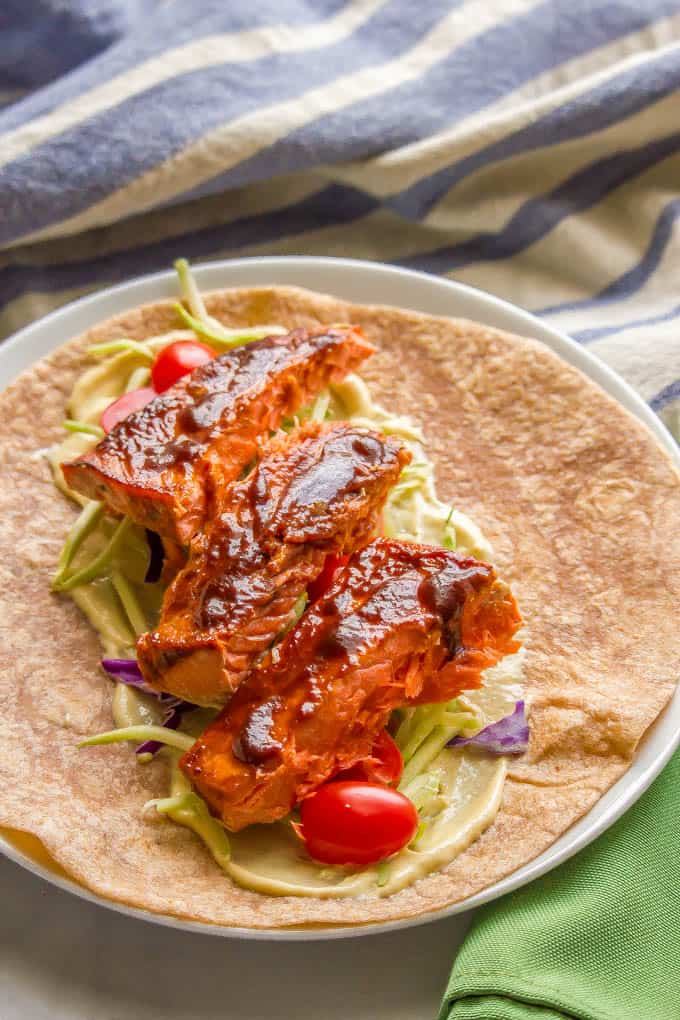 Easy BBQ roasted salmon in a wrap with coleslaw and tomatoes on a white plate