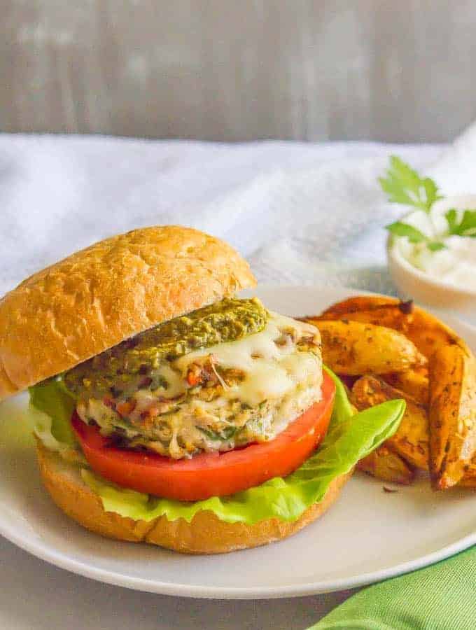 Chicken spinach burgers have just 5 ingredients and are full of cheesy shredded mozzarella, chopped fresh spinach and rich flavor from the touch of pesto. Top with extra mozzarella and pesto and serve on buns or in a lettuce wrap for a delicious, healthy burger! #chickenburger #groundchicken #healthyburger | www.familyfoodonthetable.com