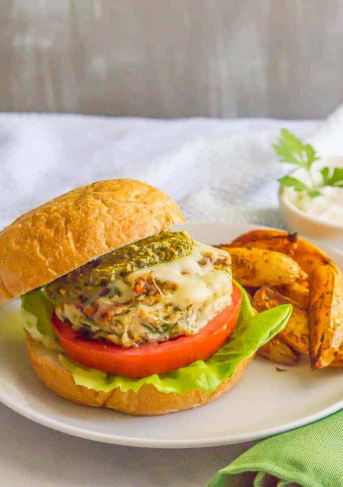 Chicken spinach burgers have just 5 ingredients and are full of cheesy shredded mozzarella, chopped fresh spinach and rich flavor from the touch of pesto. Top with extra mozzarella and pesto and serve on buns or in a lettuce wrap for a delicious, healthy burger! #chickenburger #groundchicken #healthyburger | www.familyfoodonthetable.com