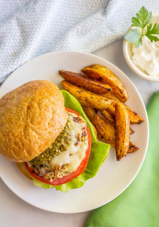 Chicken spinach burger with mozzarella and pesto on a plate with roasted potatoes