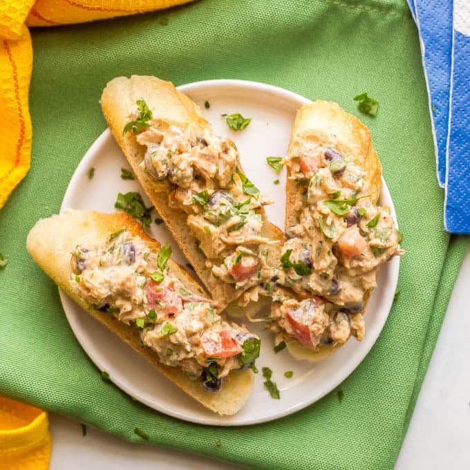 Southwests tuna salad appetizer bites on baguette slices on a white plate with a green napkin underneath