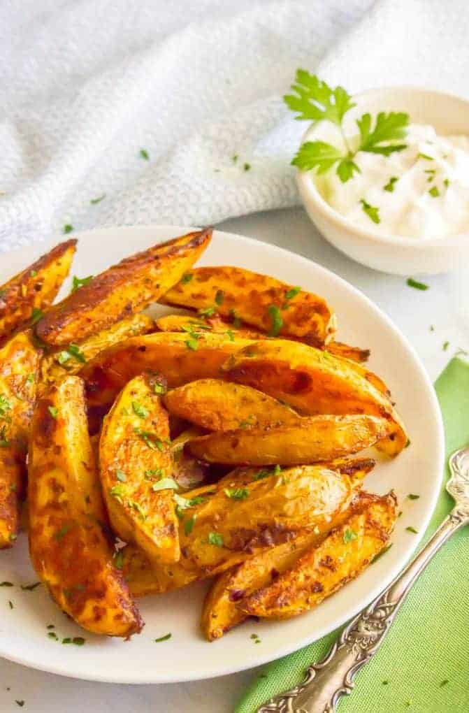 Easy spicy roasted potatoes require just a few pantry ingredients to create a truly delicious side dish with a bit of a kick! These potato wedges are crispy and crunchy on the outside with a tender, fluffy center. #roastedpotatoes #potatoes #spicyfood