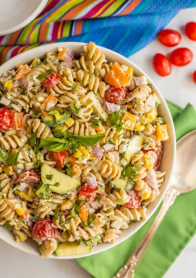 A large white bowl with a pasta salad with tons of fresh veggies and a light creamy dressing mixed in