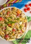 Close up of a colorful pasta salad with zucchini, peppers and tomatoes and a text overlay on the photo.