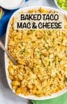 A tortilla chip topped taco style baked mac and cheese in a white baking dish with a spoon resting in it.