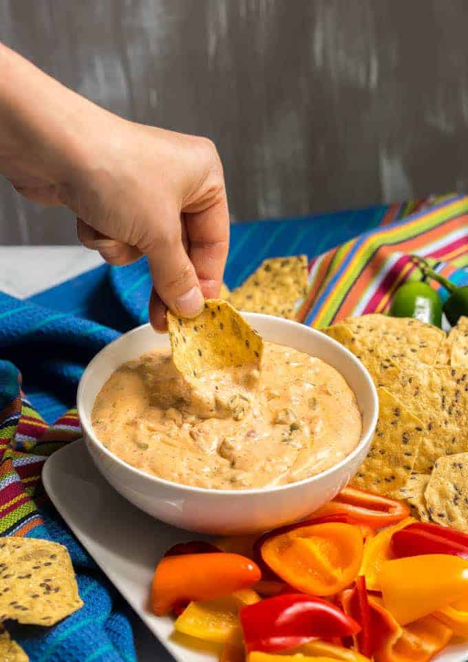 Jalapeno cream cheese dip served in a white bowl with a chip being scooped into it