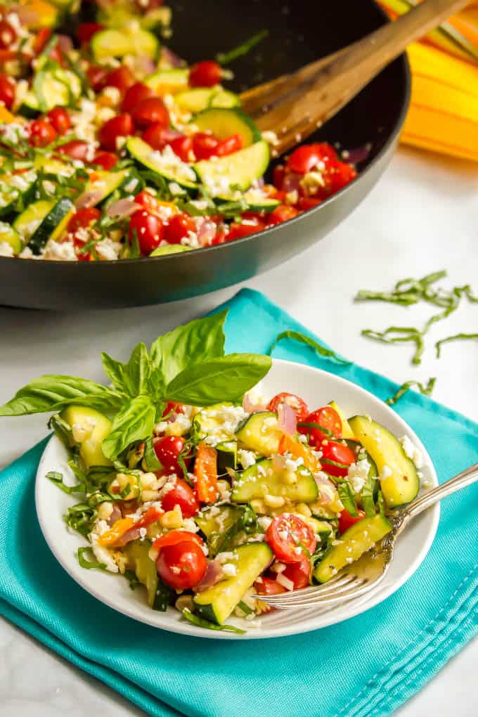 Summer veggie skillet served on a small white plate with fresh basil sprinkled on top