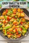 A wooden spatula resting in a dark skillet full of a homemade sweet and sour chicken with broccoli, peppers and snow peas with a text overlay on the photo.