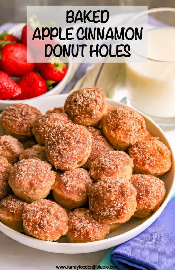 Close up of homemade baked donut holes in a large white bowl with strawberries and milk to the side.
