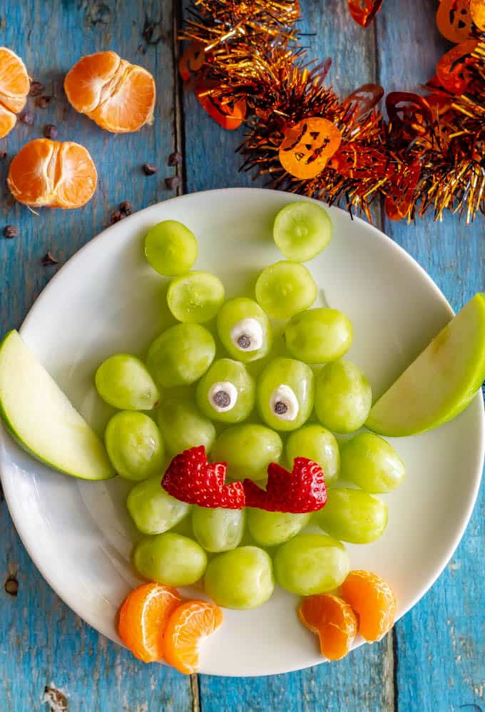 This easy green monster fruit snack plate is a cute, fun and healthy Halloween snack for kids! You can make these fruit monsters big or small and add as many arms, legs and eyes as you want! #Halloween #kidsnack #healthysnack #fruitsnack