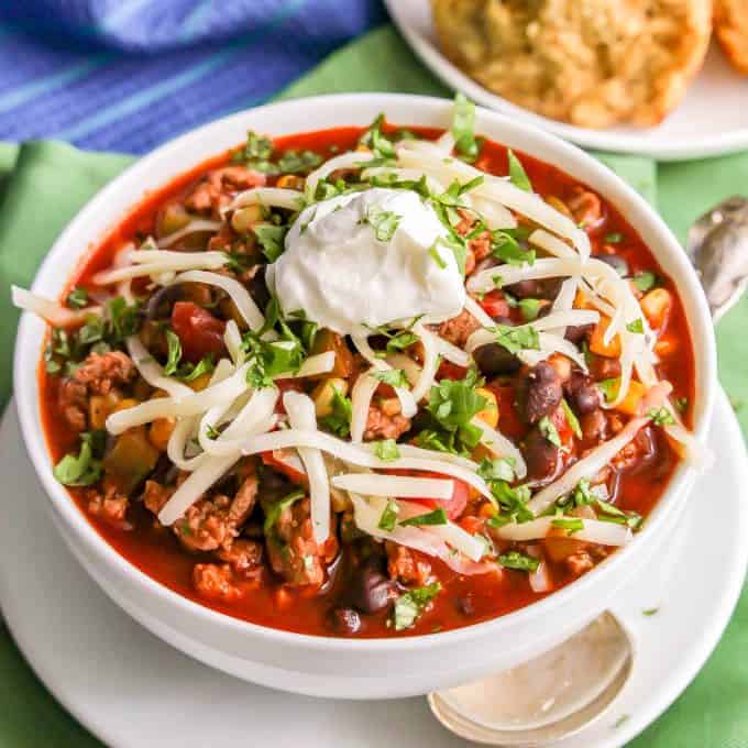 A bowl of a southwest style turkey chili with black beans with cheese, sour cream and cilantro sprinkled on top.
