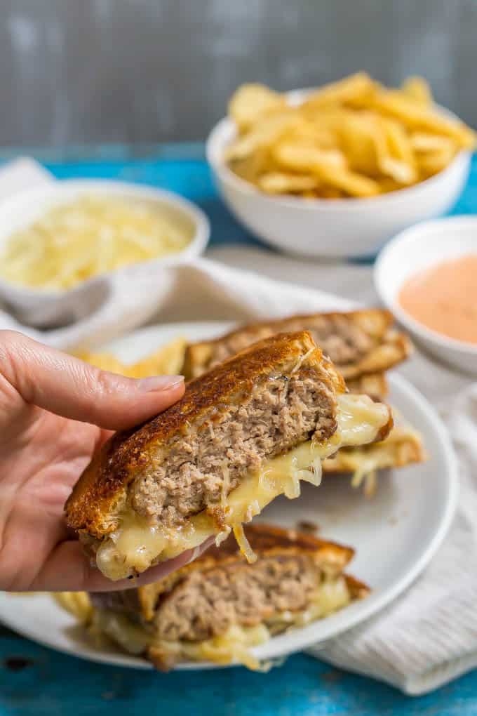 Ground turkey patty melt sandwich being held up with melty cheese