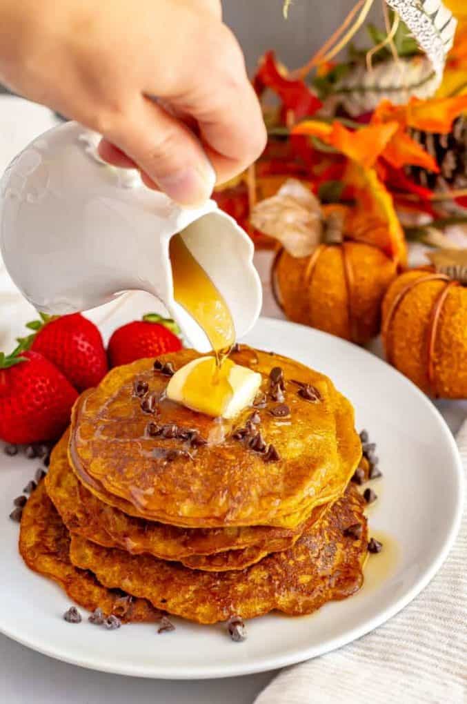 Whole wheat pumpkin pancakes are light, fluffy and full of warm spices and pumpkin flavor. They are naturally sweetened (and can be made vegan) and are perfect for a delicious fall breakfast! #pumpkin #pancakes #breakfast #vegan