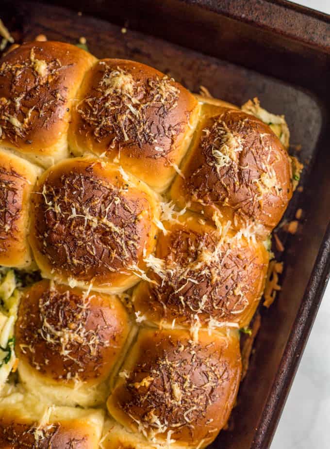 Baked pesto chicken sliders with golden brown tops in a baking pan