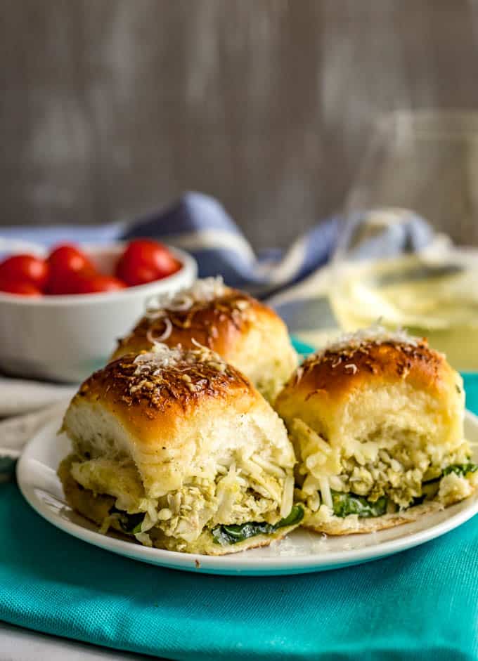 Baked pesto chicken sliders served on a white plate with a turquoise napkin underneath