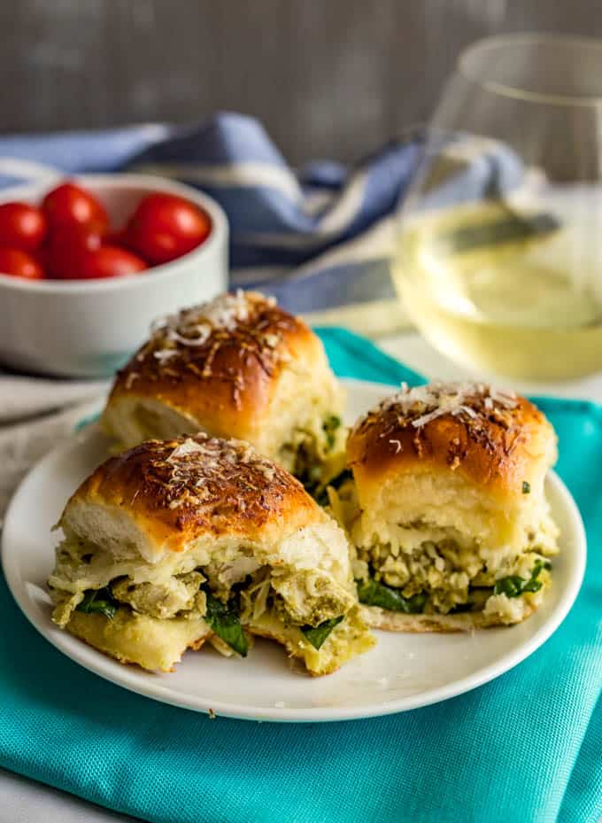 Baked pesto chicken sliders on a plate with a bite taken out of one