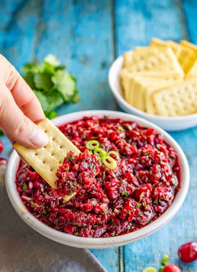 Fresh cranberry salsa with cilantro, jalapeño and citrus has big, bright flavors and comes together in just 5 minutes! Goes great with crackers or bread with cream cheese for an appetizer, served with chips, over baked brie or on sandwiches! #Thanksgivingrecipes #holidayrecipes #holidayapptizer #cranberries #salsa