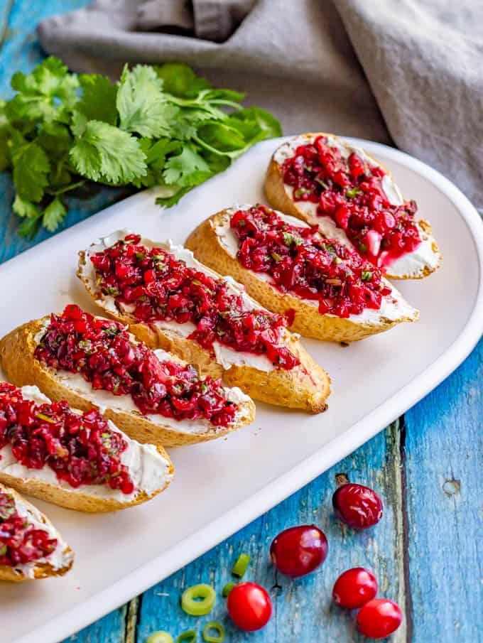 Baguette slices with cream cheese and fresh cranberry salsa on a white platter