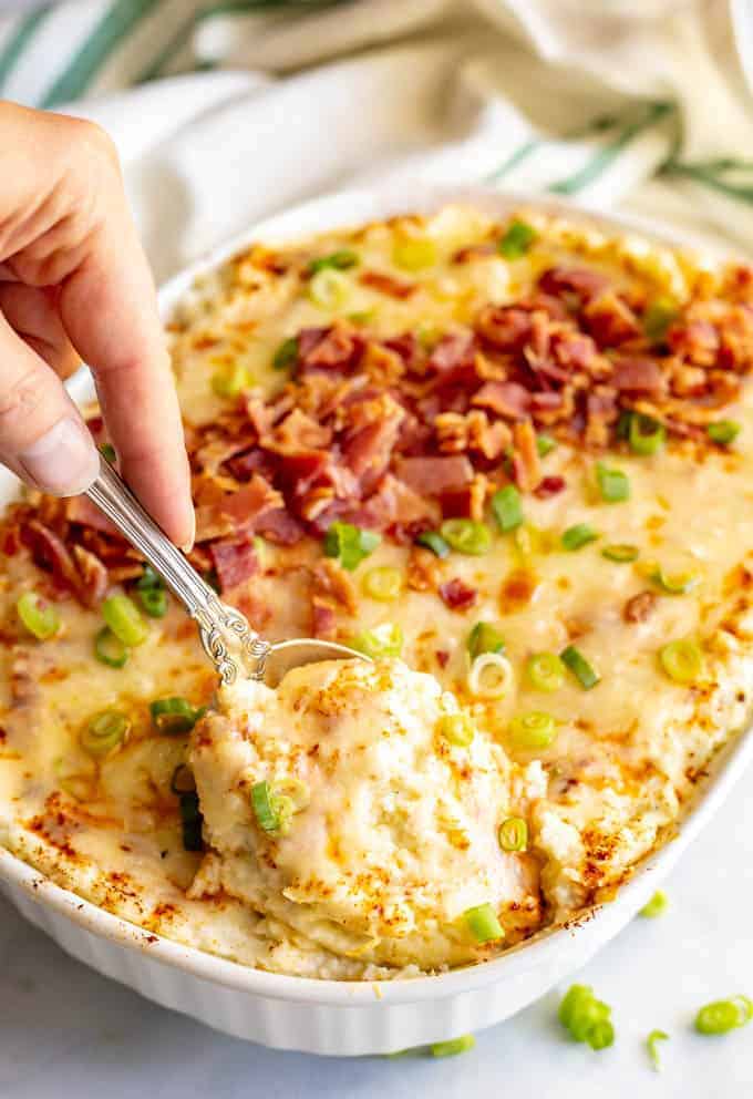 Mashed cauliflower casserole is loaded with cream cheese and cheddar cheese and served with bacon and green onions. This easy recipe is perfect for a low-carb holiday side dish! #cauliflower #lowcarb #glutenfree #holidays #sidedish #Thanksgiving #Christmas