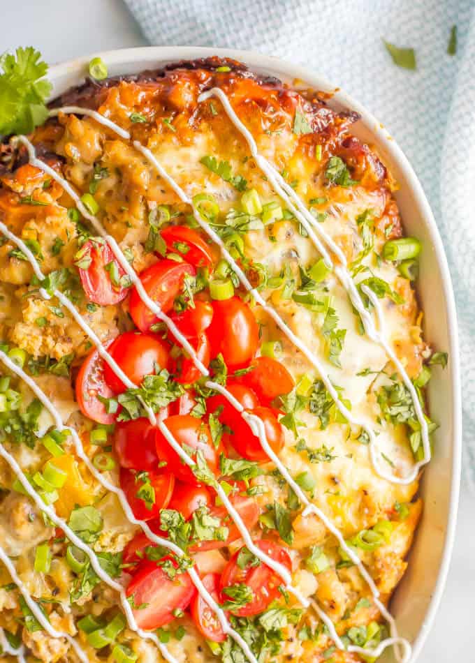 Close-up of healthy overnight slow cooker breakfast casserole in a white baking dish with tomatoes and green onions and cilantro sprinkled on top