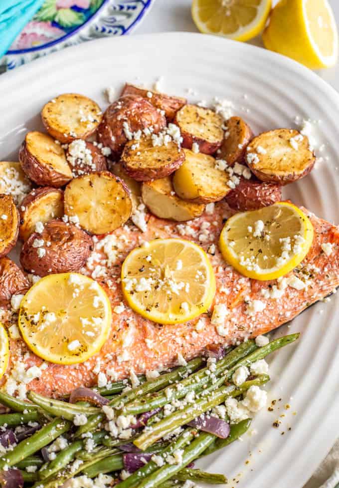 Close-up of one-pan roasted salmon and potatoes with green beans in a large white serving dish