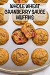 A muffin tin full of baked cranberry sauce muffins with one split open to show the insides.