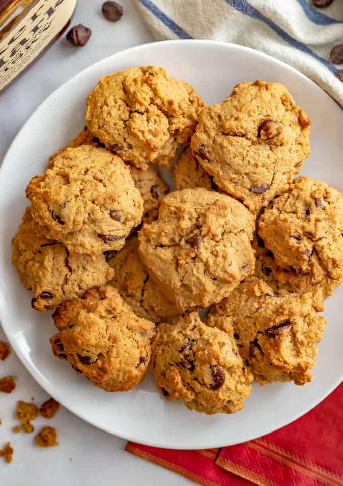Bourbon chocolate chip cookies piled up on a white plate set on a red charger.