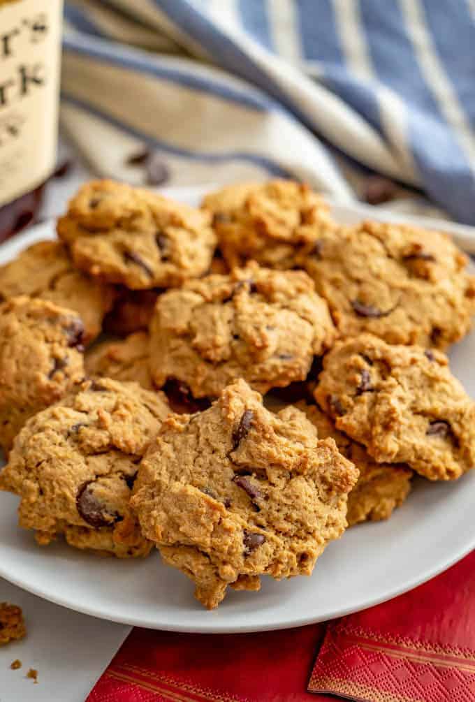 A plate full of bourbon chocolate chip cookies with a bottle of Maker's Mark in the background.