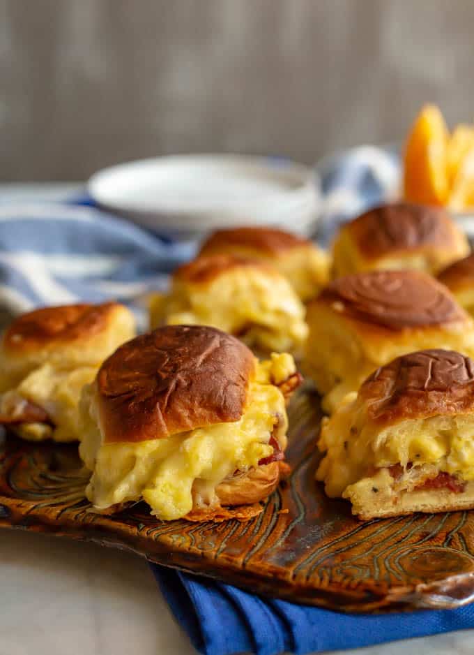 Bacon egg and cheese sliders on a dark cutting board.