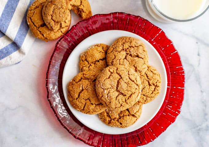 Overhead of old fashioned soft molasses cookies piled on a white plate with a red serving plate underneath