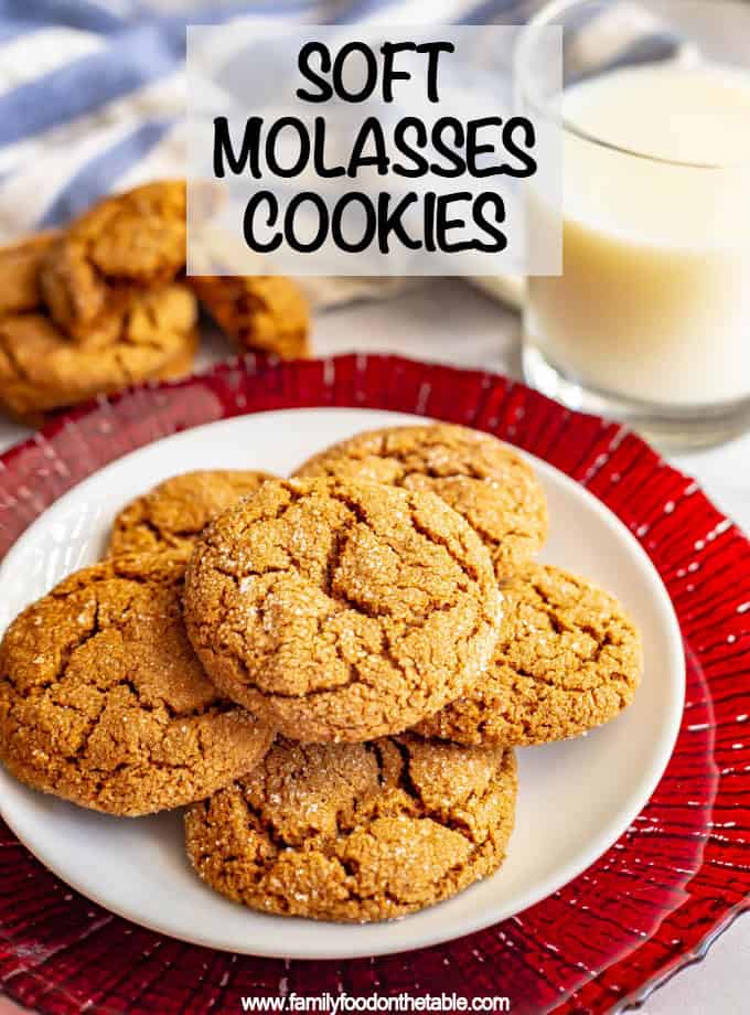A serving plate of molasses cookies set on a red charger with glass of milk in the background.