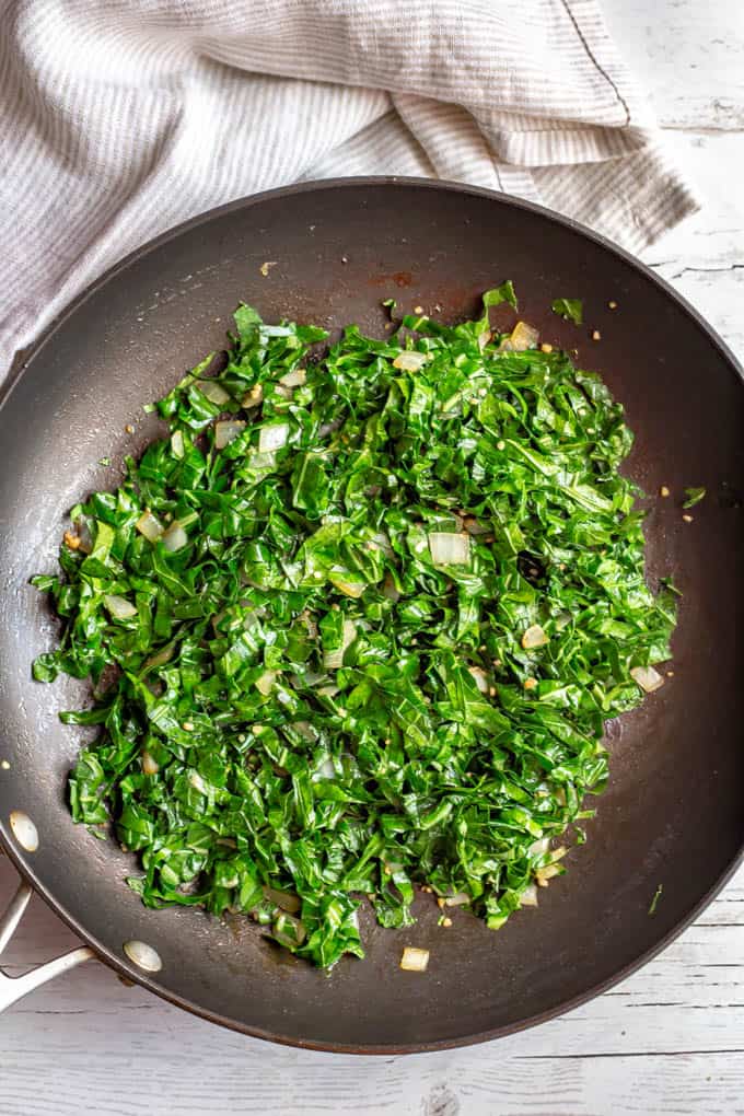 Wilted collard greens with onion in a saute pan