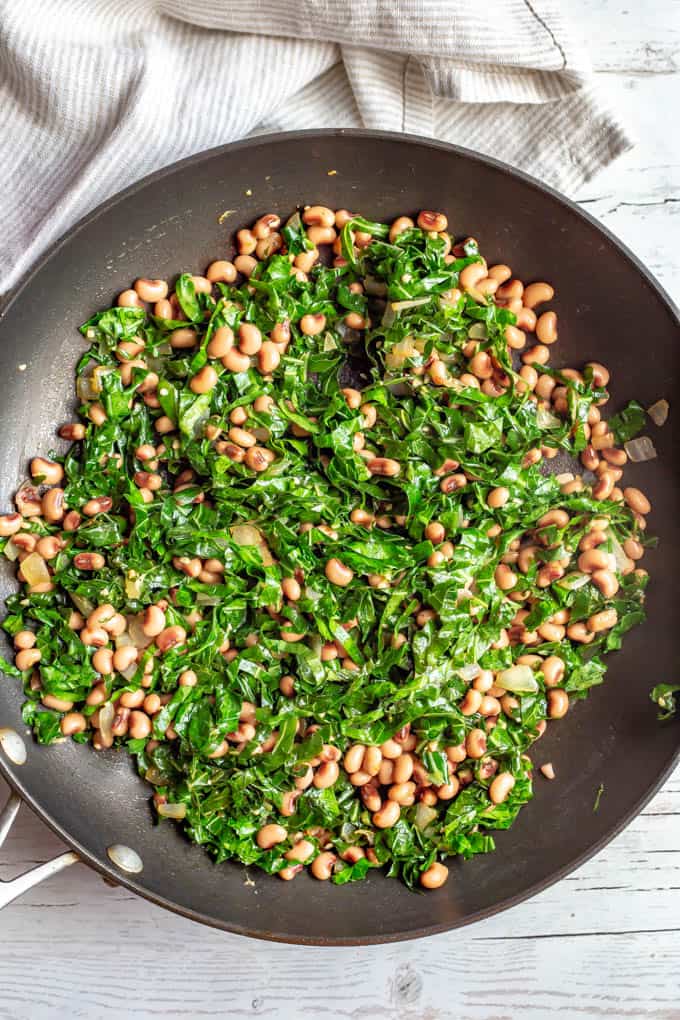 Wilted collard greens and beans in a saute pan