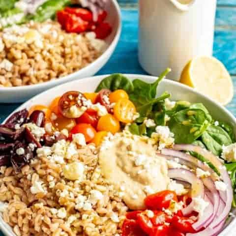 Vegetarian Greek grain bowls are loaded with wholesome grains and veggies and topped with an easy red wine vinaigrette for a beautiful and delicious lunch or light dinner! #grainbowl #mealprep #vegetarian #lunchideas #mediterraneanfood