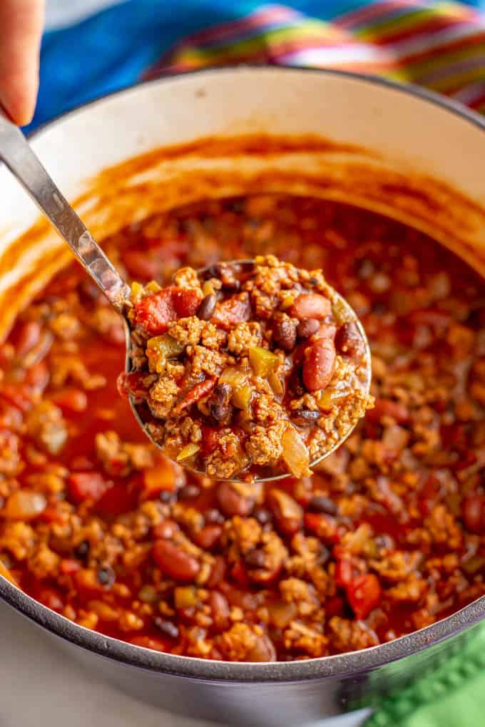 Large cooked pot of game day chili with meat and beans and a ladle being served up