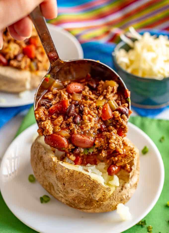 Loaded chili stuffed baked potatoes are the perfect way to use up leftover chili! Tender, fluffy potatoes are filled with warm chili and topped with all your favorite toppings. #chili #potatoes #bakedpotatoes #stuffedpotatoes #easydinner