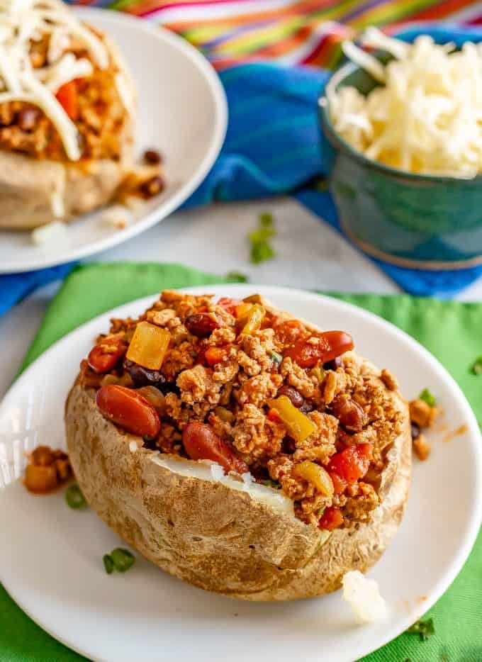 Chili stuffed baked potato on a white plate