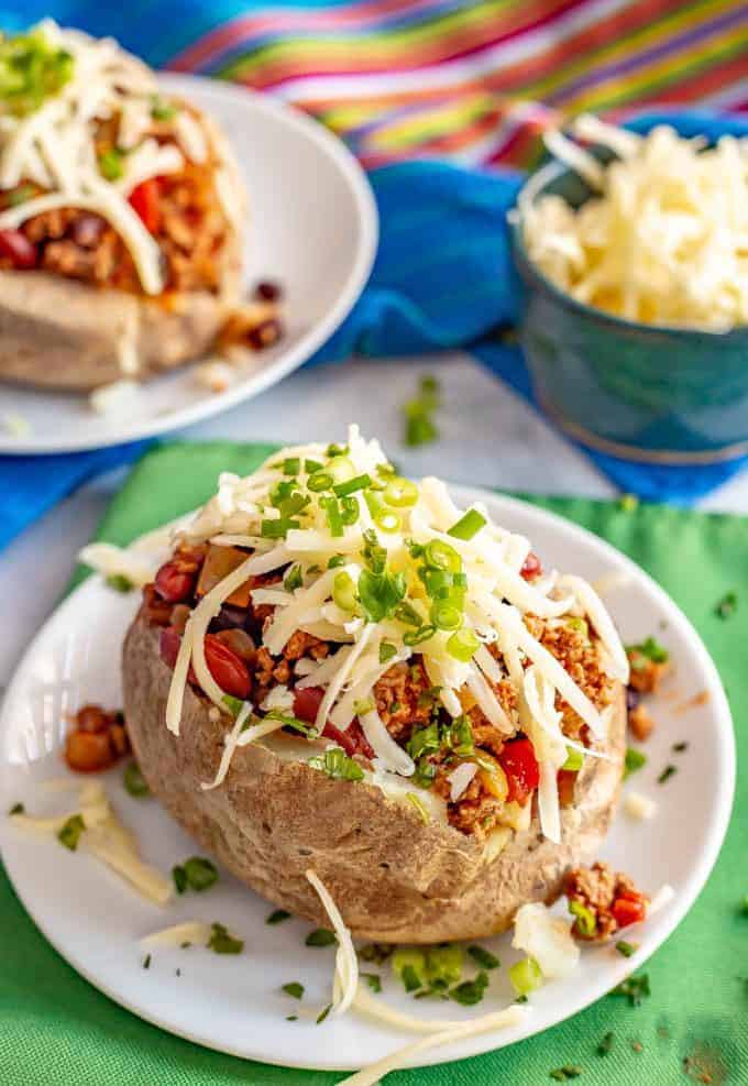 Loaded chili stuffed baked potatoes are the perfect way to use up leftover chili! Tender, fluffy potatoes are filled with warm chili and topped with all your favorite toppings. #chili #potatoes #bakedpotatoes #stuffedpotatoes #easydinner