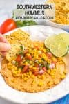 A hand dipping a tortilla chip into a bowl full of hummus topped with corn and pico de gallo.