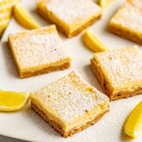 Healthier lemon bars have a shortbread crust and a silky smooth slightly sweet, slightly tart creamy lemon filling on top. These bars are whole wheat and naturally sweetened - and just 7 ingredients! #lemonbars #lemonsquares #lemon #dessert
