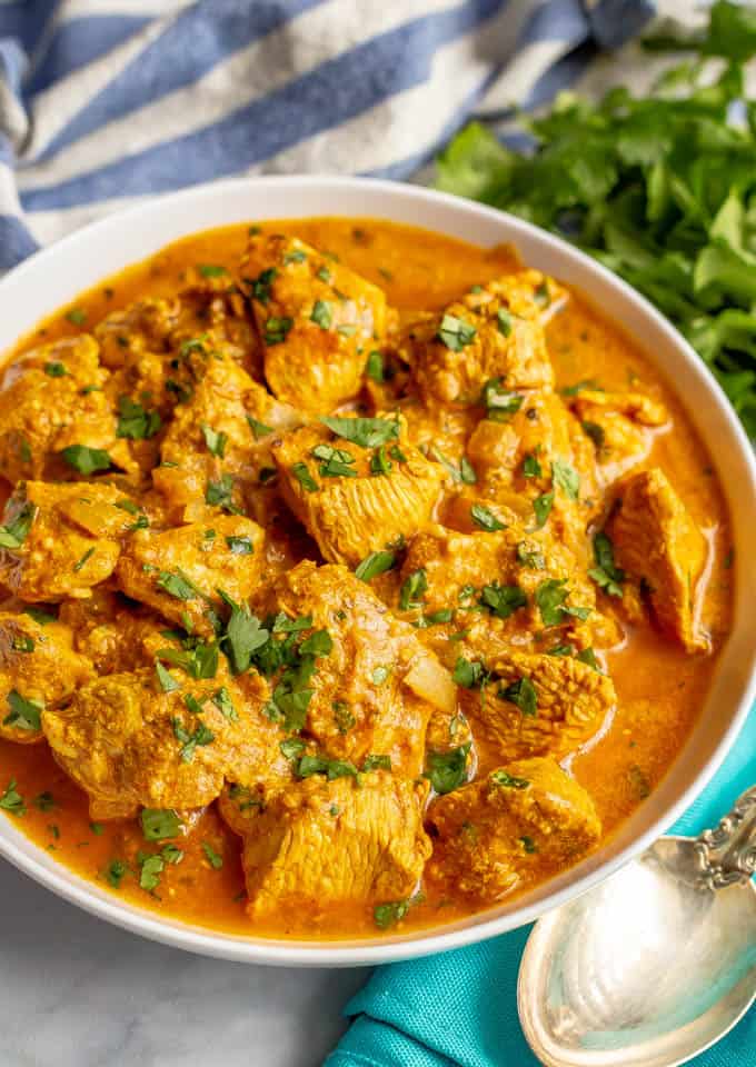 Creamy butter chicken recipe sprinkled with parsley and served in a white bowl