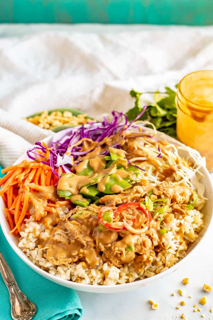 Close up of a peanut chicken rice bowl with carrots, cabbage and snow peas.