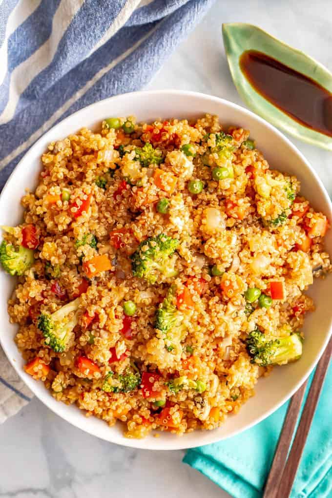 Vegetarian quinoa fried rice served in a large white bowl with a small bowl of soy sauce nearby