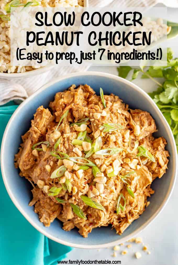A blue tinted bowl full of a slow cooker shredded peanut chicken  with sliced green onions and chopped peanuts sprinkled on top.