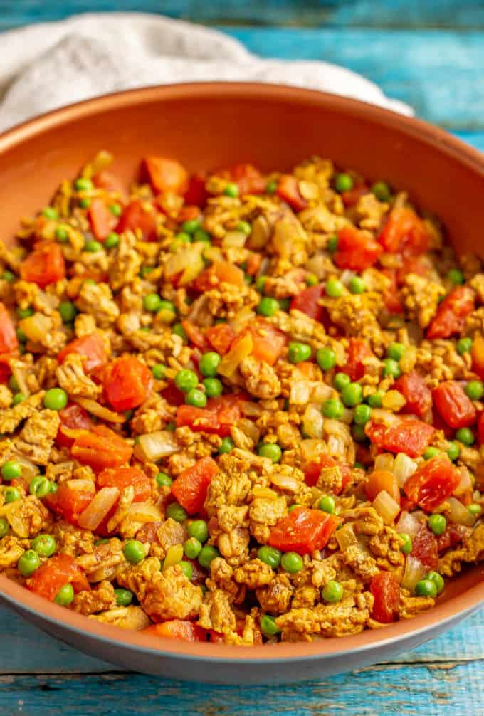 Cooked ground turkey curry with peas and tomatoes in a large skillet
