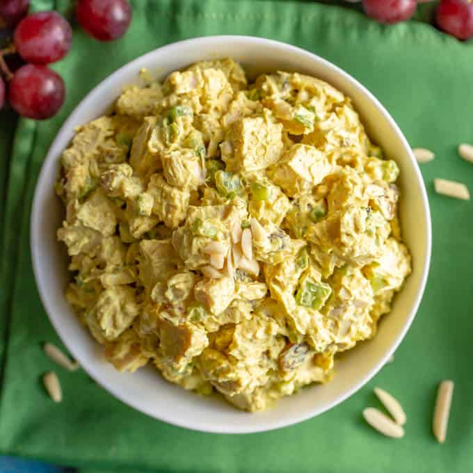 Healthy curry chicken salad in a white bowl set on a green napkin