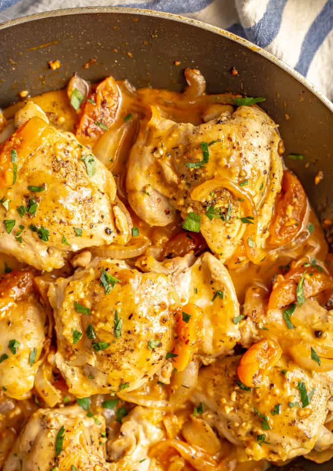 Chicken thighs in an apricot sauce in a large dark skillet.