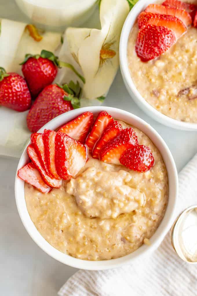 Close up of a bowl of creamy slow cooker oatmeal with fresh, sliced strawberries on top.