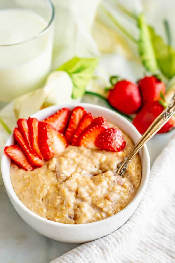 Bowl of slow cooker strawberries and cream oatmeal served with extra strawberries on top